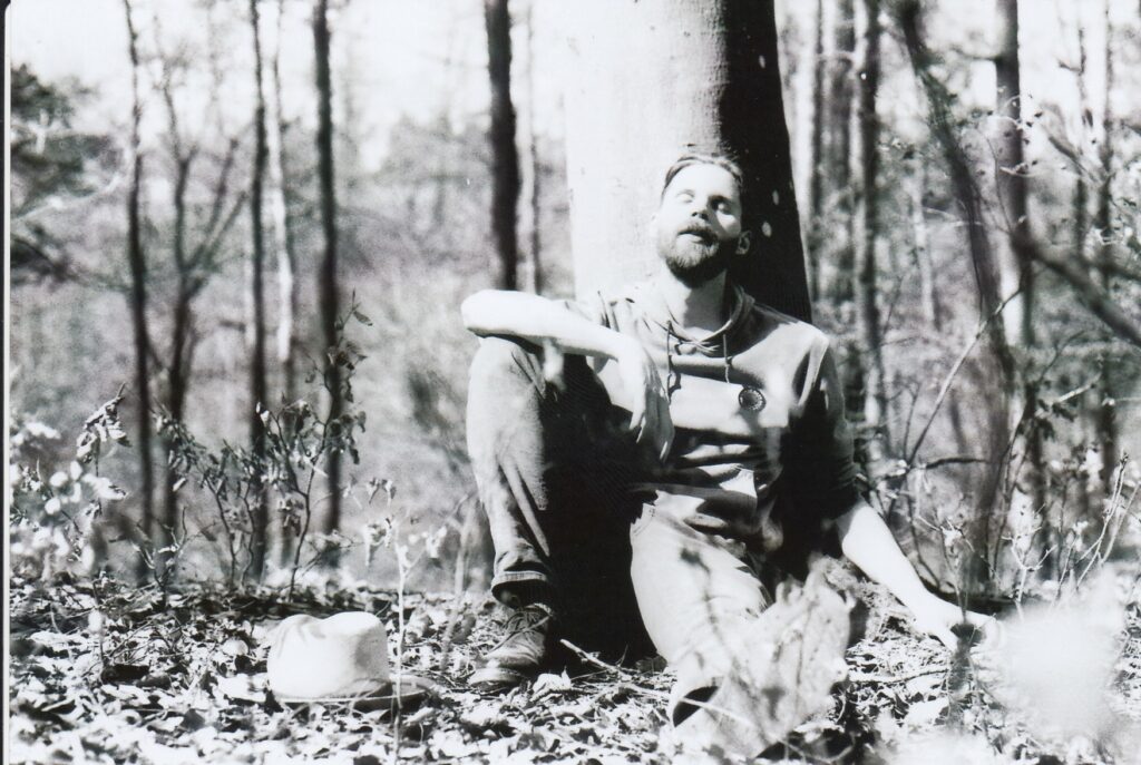 Mann sitzt auf Waldboden in der Sonne